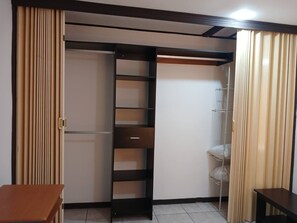 Ein Zimmer mit Schiebetürenschrank, einem kleinen Tisch und einem Regal.