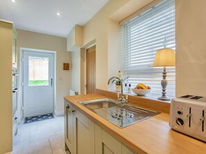 A kitchen with a built-in sink, a window with blinds, a toaster, and a bowl of fruit on the counter. - 2 Bed in Hexham (oc-79240) (Kielder)