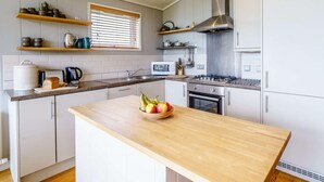 Une cuisine moderne dotée d’un îlot central, d’un four encastré et d’appareils électroménagers en acier inoxydable.