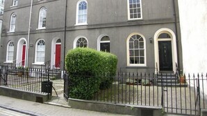A two-story building with a symmetrical facade, arched windows, and a central entrance. - 4 Bed in Tenby (oc-fb104) (Tenby)