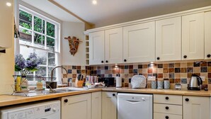 A kitchen with a washing machine, dishwasher, and tiled backsplash. - 4 Bed in Tenby (oc-fb104) (Tenby)