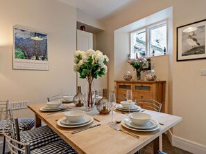 A dining area with a long table set for six, surrounded by chairs. - 4 Bed in Tenby (oc-fb104) (Tenby)
