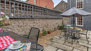 A patio with a table, chairs, and an umbrella. - 4 Bed in Tenby (oc-fb104) (Tenby)