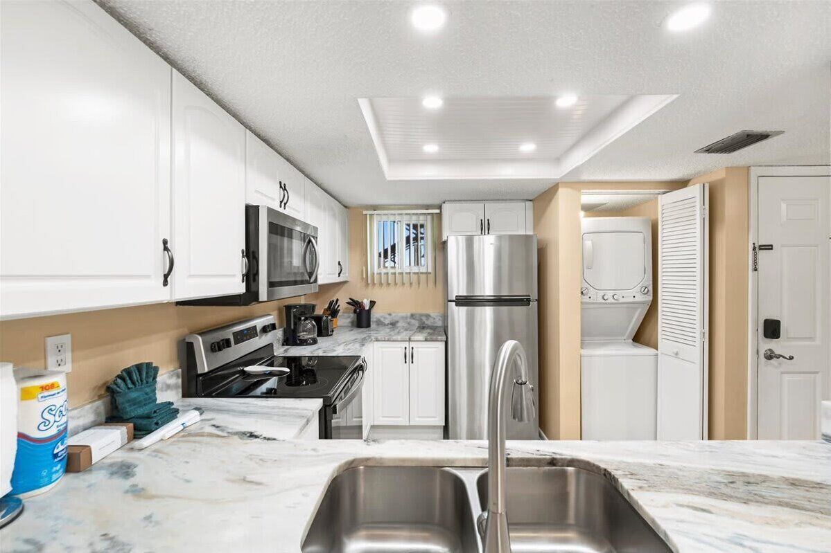 A modern kitchen with white cabinets, stainless steel appliances, and a marble countertop.