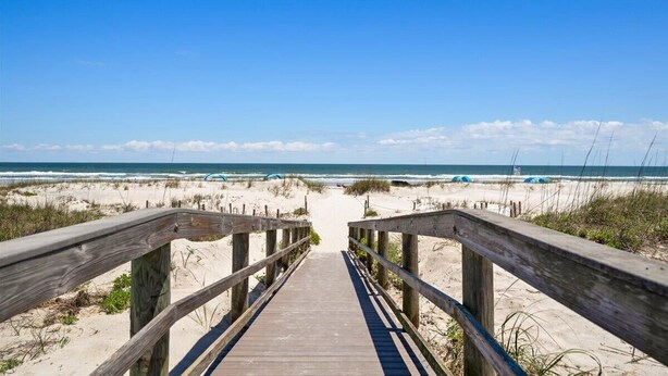 A wooden boardwalk leading to a beach with sand dunes and the ocean in the background. - Ocean Village Club K35 (St. Augustine)