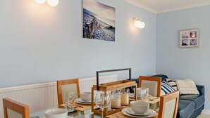 En matplats med ett glasbord, stolar och en blå soffa i bakgrunden.