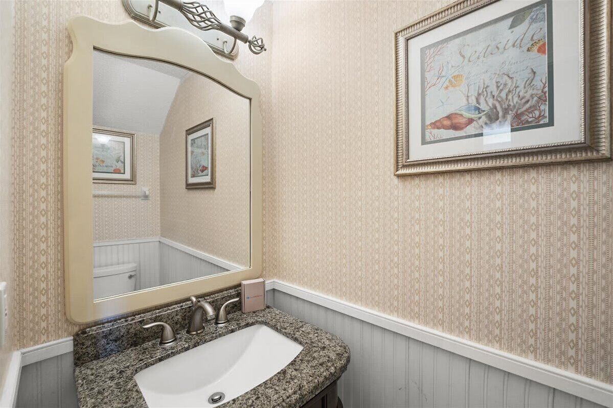 Un baño con un espejo grande, un lavamanos y un cuadro en la pared.