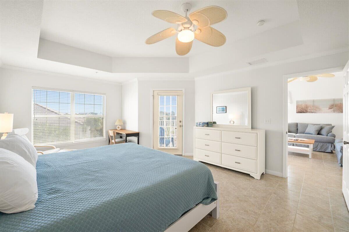 Um quarto com uma cama, cômoda, escrivaninha e ventilador de teto.