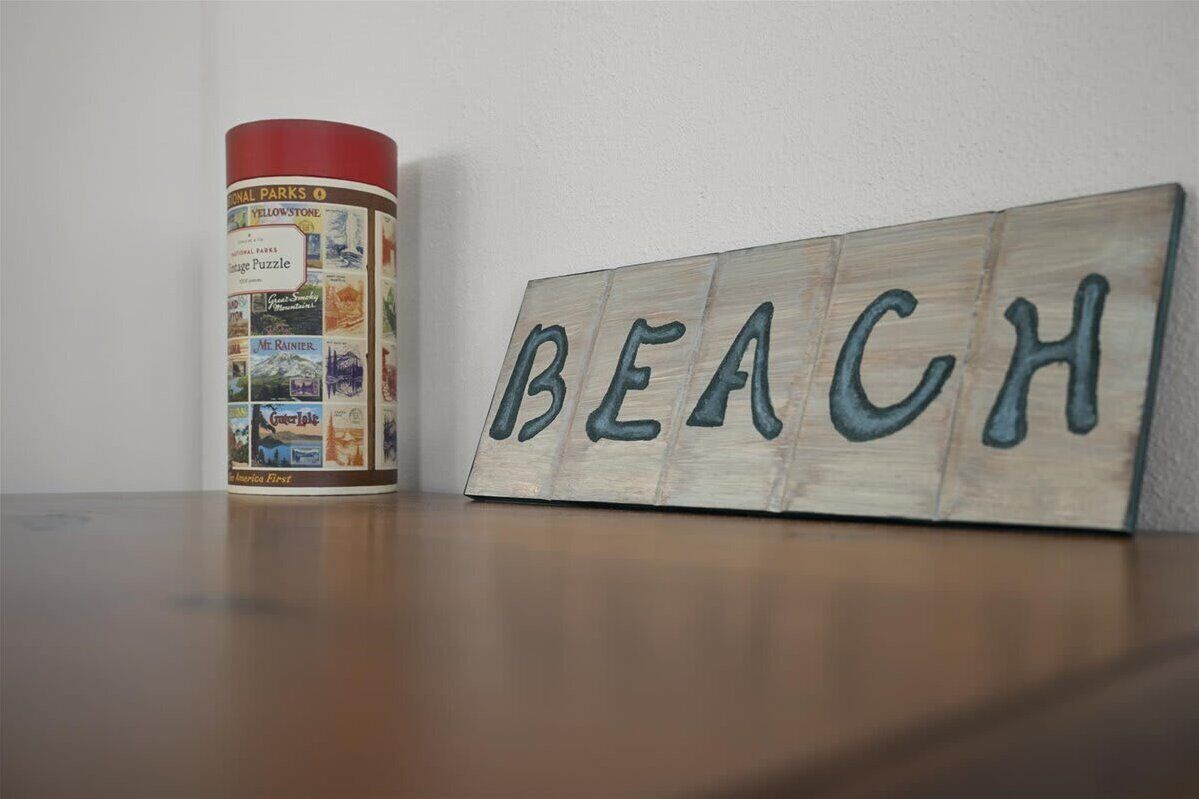 A wooden sign with the word "BEACH" and a cylindrical container with images of parks and landmarks.