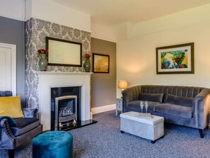 A living room with a fireplace, a sofa, a chair, and a coffee table. - 2 Bed in Eastbourne (oc-83735) (Eastbourne)