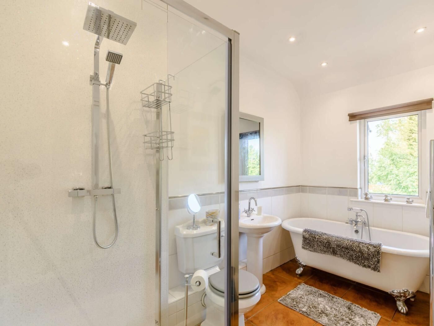 Ein modernes Badezimmer mit einer Glasdusche, einer freistehenden Badewanne, einem Waschbecken auf Säule und einer Toilette.