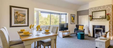 A modern living room with a dining area, a fireplace, and artwork on the walls.