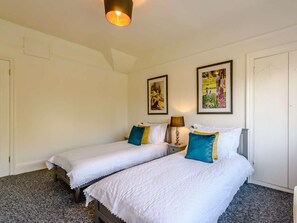 A hotel room with two beds, a nightstand, a lamp, and two framed artworks on the wall. - 2 Bed in Eastbourne (oc-83735) (Eastbourne)