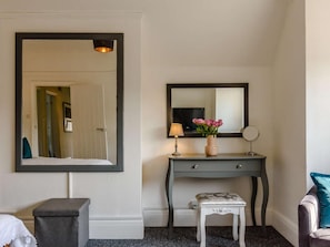 A hotel room with a large mirror, a bedside table with a lamp, a small stool, and a television. - 2 Bed in Eastbourne (oc-83735) (Eastbourne)