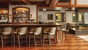 A bar area with a wooden bar counter, multiple stools, and a variety of bottles. There are chairs and a fireplace in the background. - The Ritz-Carlton Club®, Vail
Charming 3-bedroom hotel with AC in fabulous Vail (Vail)