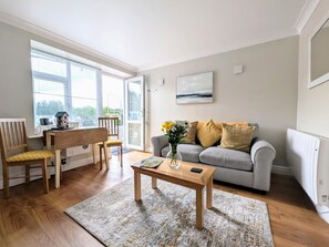 A living room with a sofa, a coffee table, a chair, a small table with a lamp, and a window with a view. - 1 Bed in Keswick (oc-sz468) (Keswick)