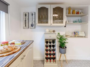 A kitchen with white cabinetry, a wine rack, and a potted plant. - 3 Bed in Cullompton (oc-85389) (Willand)