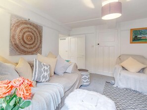A living room with a sofa, armchairs, a coffee table, and a rug. There is a door and a painting on the wall. - 3 Bed in Cullompton (oc-85389) (Willand)
