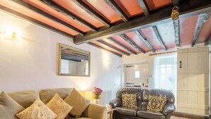 Un salon avec un canapé beige, un canapé en cuir noir, un miroir et un plafond en bois.