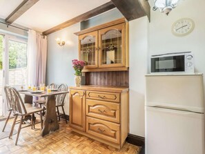 Eine Küche mit Holzausstattung, einer Mikrowelle und einem Essbereich mit Stühlen und Tisch.