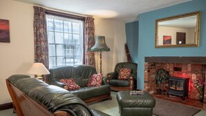 A living room with a sofa, armchair, ottoman, fireplace, and a mirror on the wall. - 3 Bed in Cromer (oc-88327) (Northrepps)