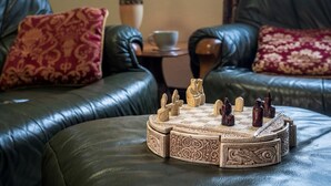 A living room with a chessboard, leather sofas, patterned cushions, a lamp, and a cup on a side table. - 3 Bed in Cromer (oc-88327) (Northrepps)