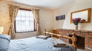 A bedroom with a bed, a window with curtains, a fireplace, and a mirror on the wall. - 3 Bed in Cromer (oc-88327) (Northrepps)