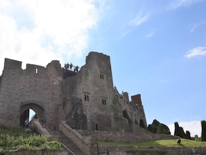 A historic castle with a large archway entrance, a central tower, and a staircase leading up to the main entrance.