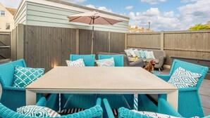 Un'area patio con tavolo e sedie, una recinzione in legno e un cielo sereno.