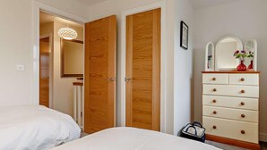 A bedroom with two beds, a wooden wardrobe, a dresser with drawers, a mirror, and a hanging light fixture. - 2 Bed in Appledore (oc-90648) (Appledore)