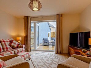 Ein gemütliches Wohnzimmer mit einer Couch, einem Fernseher und Blick ins Freie.