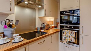A modern kitchen with a built-in oven, a toaster, and a variety of utensils in a container. - 2 Bed in Appledore (oc-90648) (Appledore)