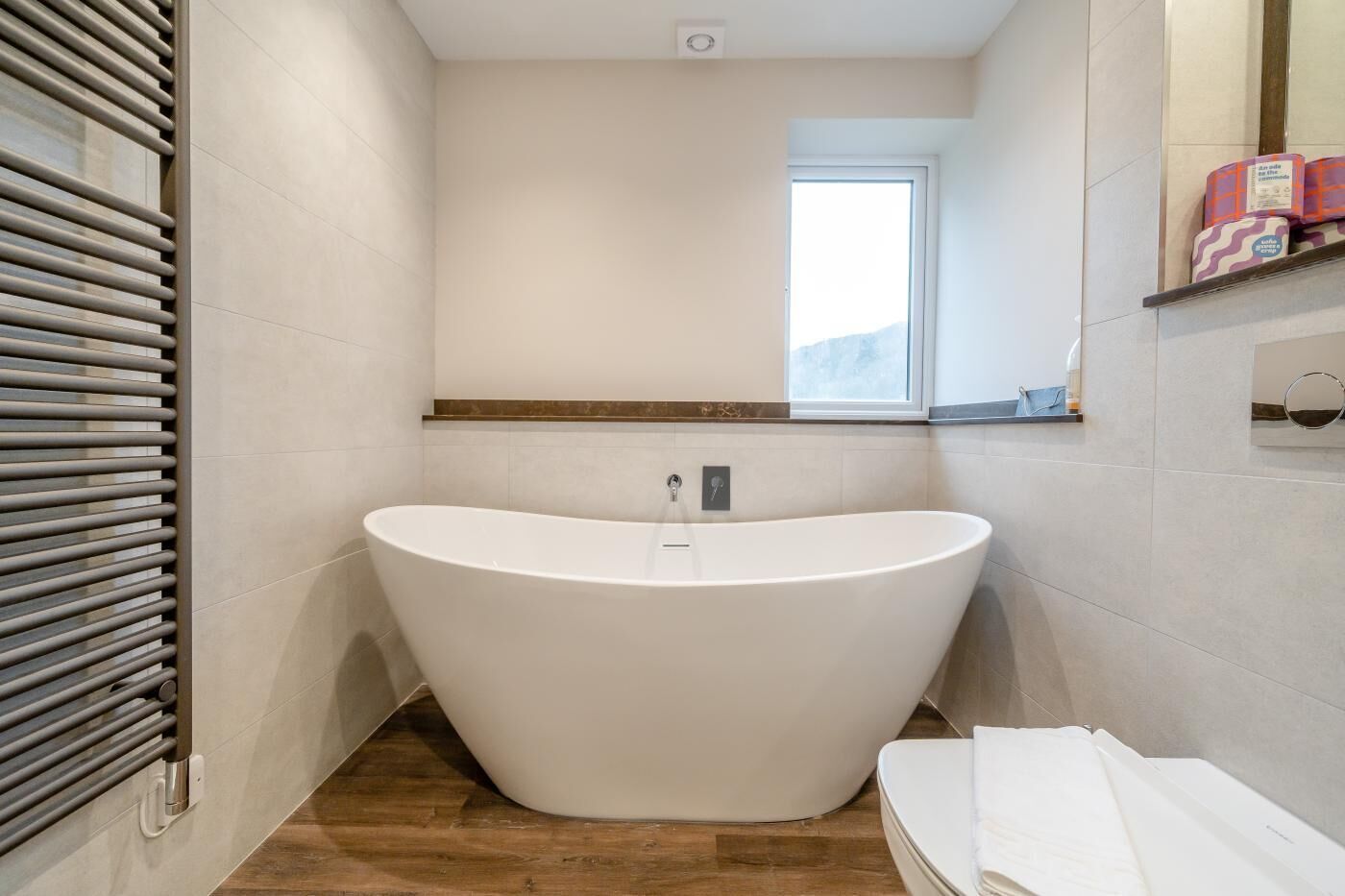 Une salle de bain moderne avec une baignoire sur pieds, une fenêtre et un porte-serviettes.