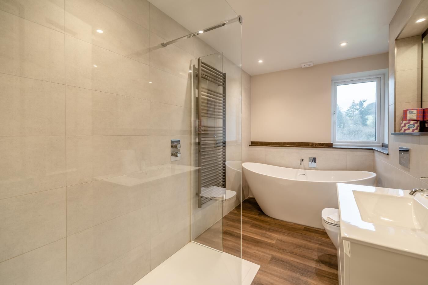 Ein modernes Badezimmer mit einer freistehenden Badewanne, einer Glasdusche und einem großen Fenster, das für natürliches Licht sorgt.