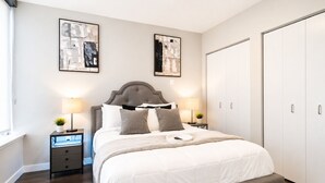 A bedroom with a bed, bedside tables, a wardrobe, and two abstract paintings on the wall. - The Skyline Suite Midtown (Atlanta)