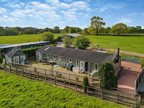 A large house with a deck, surrounded by a fenced property.