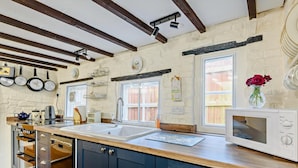 A kitchen with wooden cabinets, a sink, a microwave, and a window with a view. - 2 Bed in Horncastle (oc-93375) (Belchford)