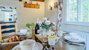 A dining table set with plates, bowls, cutlery, and a bottle of wine, with a window and curtains in the background. - 2 Bed in Horncastle (oc-93375) (Belchford)
