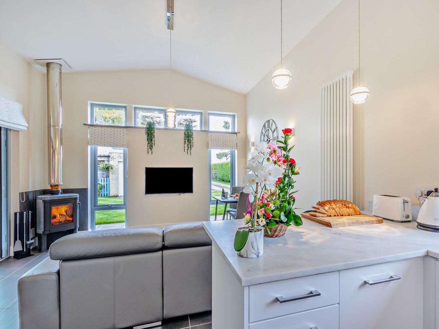 A modern kitchen with a built-in stove, a flat-screen TV, and a dining area with a bench.