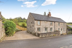 A stone house with a gravel driveway and a wooden fence. - 5 Bed in Matlock (oc-93585) (Brassington)