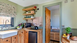 A compact kitchen with wooden cabinets, a built-in sink, a microwave, and a small refrigerator.