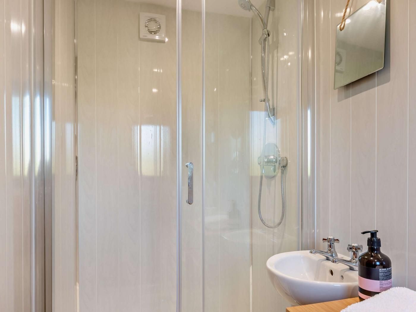 Une salle de bain moderne avec une douche à parois de verre, un lavabo blanc et un miroir.