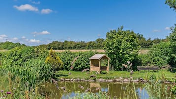 Un jardin paisible avec un étang, une structure en bois et un banc.