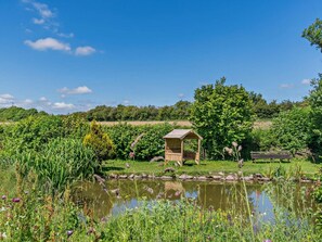 A serene garden with a pond, a wooden structure, and a bench. - 1 Bed in Hawarden (oc-93595) (Dobshill)