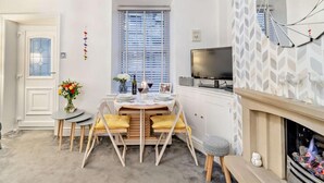 Ein gemütlicher, kleiner Wohnbereich mit Essplatz, Fernseher und Kamin.