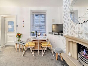 Ein gemütlicher, kleiner Wohnbereich mit Essplatz, Fernseher und Kamin.