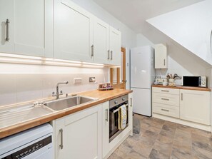 A modern kitchen with white cabinetry, a wooden countertop, a built-in oven, and a microwave. - 2 Bed in Morecambe (oc-93719) (Heysham)