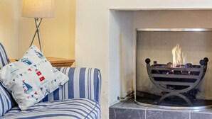 Een kamer met een bank, een lamp en een open haard.
