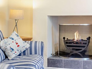 Ein Zimmer mit einer Couch, einer Lampe und einem Kamin.