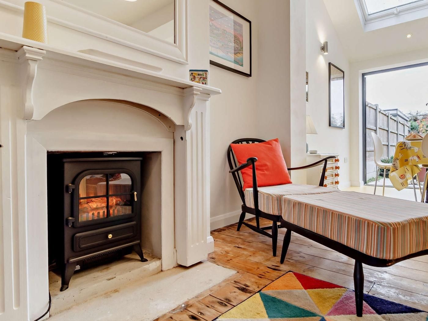 A room with a fireplace, a dining table with chairs, and a colorful rug.